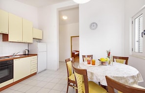 A compact kitchen with white cabinets, a dining table with chairs, and a clock on the wall. - Beautiful apartment in Necujam with WiFi (Necujam)