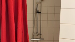 En dusch med ett duschhuvud som kan hållas i handen, en borste som kan hållas i handen och en väggmonterad kran.