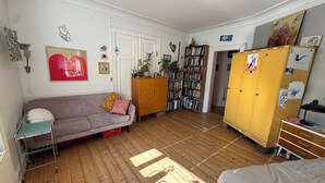 Ett rum med en soffa, en säng, en bokhylla, en garderob och en dörr.