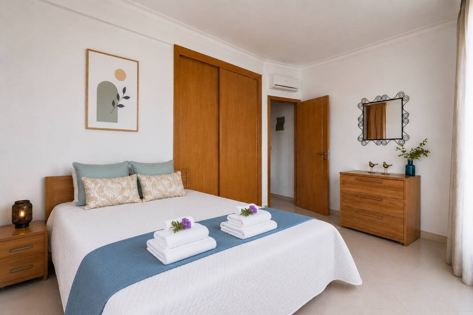Quarto com cama, cômoda, espelho e porta.