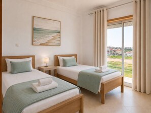 Ein Hotelzimmer mit zwei Betten, einem Strandbild und Blick auf eine Wohngegend.