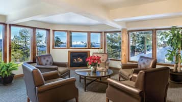 A cozy room with leather chairs, a fireplace, and large windows offering a mountain view.