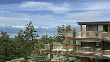 A multi-story building with a registration sign, surrounded by trees and a view of mountains and a lake.