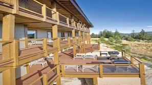Un edificio de varios pisos con terrazas exteriores, barandas de madera y zonas de estar al aire libre.