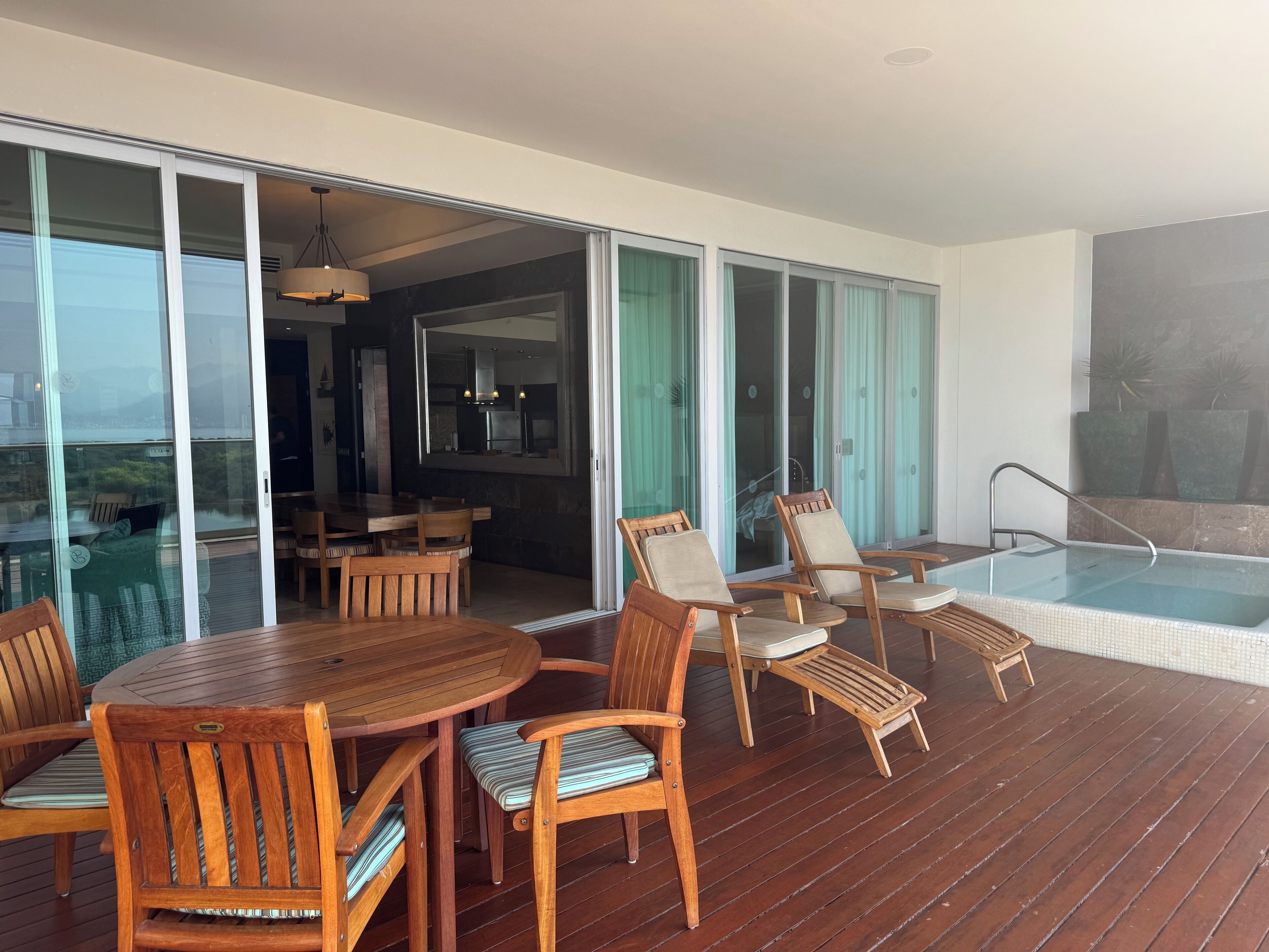 A wooden deck with a pool, outdoor seating, and a view of the city.