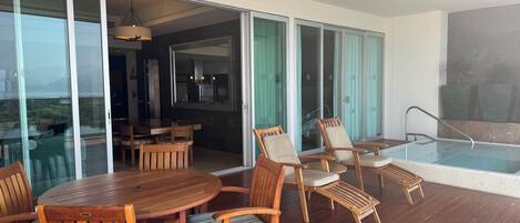 A wooden deck with a pool, outdoor seating, and a view of the city.