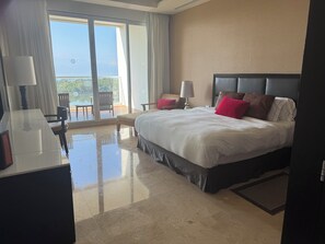 Ein Hotelzimmer mit einem großen Bett, einem Schreibtisch, einem Sessel und Blick ins Freie.