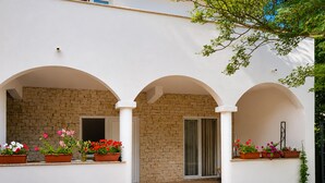 Un edificio con tres entradas arqueadas, un muro de ladrillo y plantas en macetas.