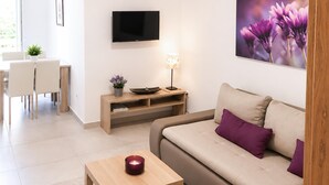 Una sala de estar moderna con un sofá, una mesa de centro, un televisor y un comedor con sillas y una mesa.