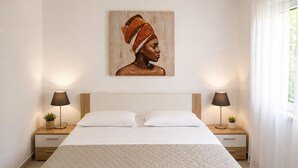 Un dormitorio con una cama grande, dos mesitas de noche con lámparas, un cuadro en la pared y una ventana con cortinas.