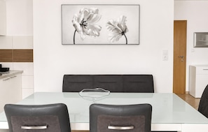 A modern dining area with a glass table, two leather chairs, a grey cushioned bench, and a framed floral artwork on the wall. - Stunning apartment in Tribanj Sibuljina with WiFi (Tribanj Sibuljina)
