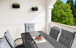 A balcony with a table, chairs, and two black wall-mounted planters with greenery. - Stunning apartment in Tribanj Sibuljina with WiFi (Tribanj Sibuljina)
