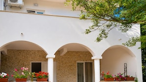 Un edificio con tres ventanas arqueadas, pared de ladrillo y macetas con flores.