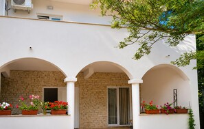 A building with three arched windows, a brick wall, and potted plants with flowers. - 1 bedroom gorgeous apartment in Tribanj Sibuljina (Tribanj Sibuljina)