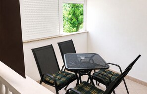 A balcony with a table and chairs, a window with blinds, and a view of greenery outside. - 1 bedroom gorgeous apartment in Tribanj Sibuljina (Tribanj Sibuljina)