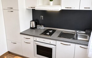 A modern kitchen with white cabinets, a black backsplash, a gas stove, a sink, and a built-in oven. - 1 bedroom gorgeous apartment in Tribanj Sibuljina (Tribanj Sibuljina)