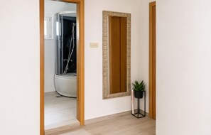 Ein Flur mit Dusche, einer Tür und einem Blumentopf.