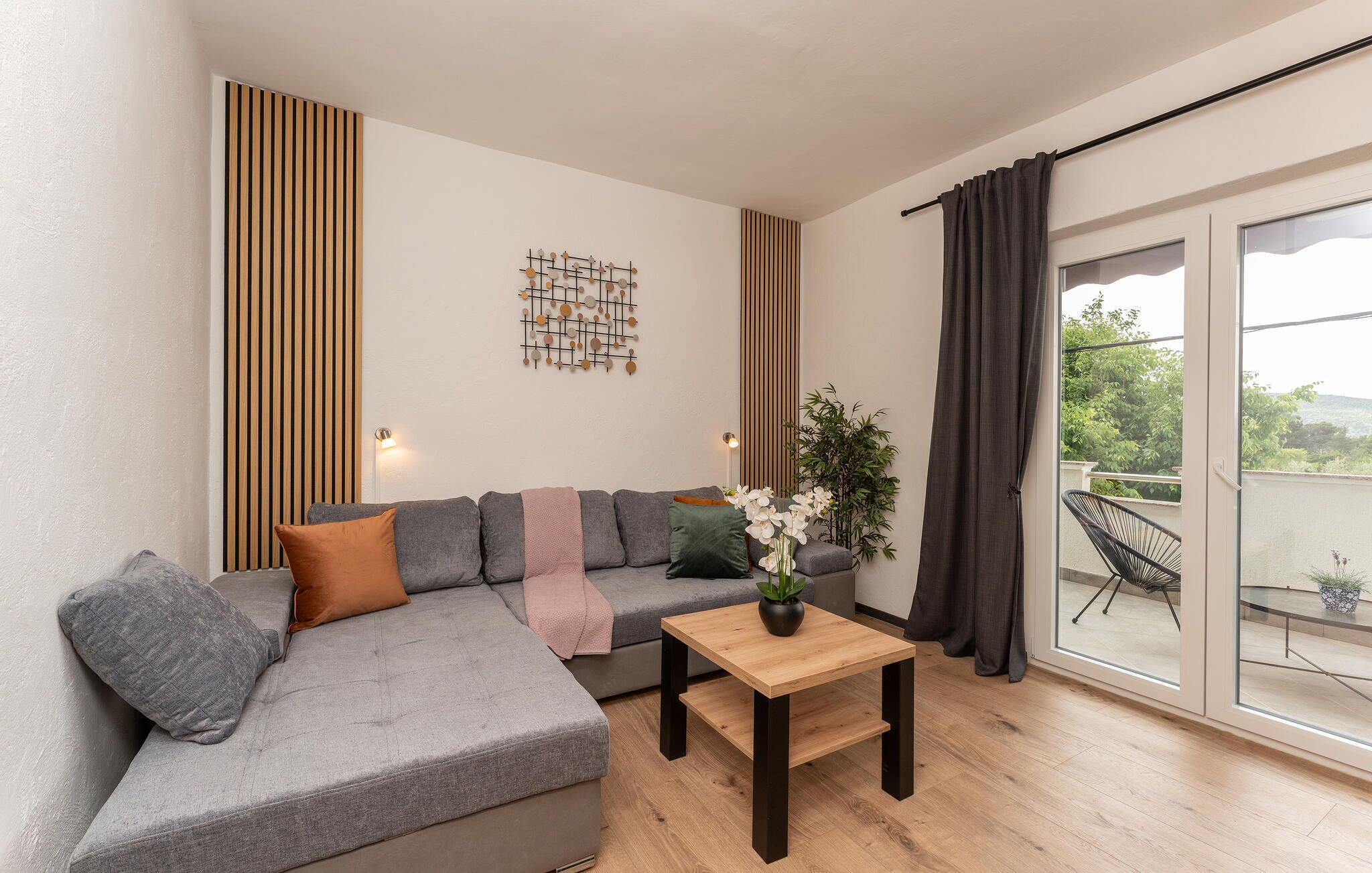 A modern living room with a grey sectional sofa, a wooden coffee table, and a decorative wall piece.