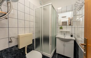 A bathroom with a toilet, a shower enclosure, a sink, and a mirror. - Beautiful home in Starigrad Paklenica (Starigrad Paklenica)