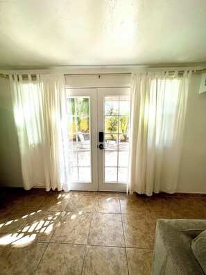 A room with a tiled floor, a door with glass panels, and white curtains.