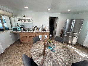 A modern kitchen with a built-in microwave, stainless steel refrigerator, and a dining area with a round wooden table.