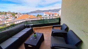 Ein Balkon mit Gartenmöbeln, Blick auf eine Stadt und ein Berg in der Ferne.