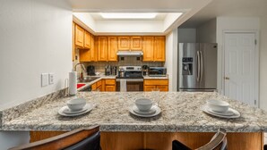 A kitchen with wooden cabinets, a stainless steel refrigerator, a microwave, and granite countertops. - Green Pines | Bunk Room, Air Hockey & Canyons (Cottonwood Heights)