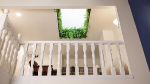A staircase with a white balustrade, a ceiling with a green plant, and a view of a room below. - Green Pines | Bunk Room, Air Hockey & Canyons (Cottonwood Heights)
