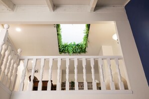 A staircase with a white balustrade, a ceiling with a green plant, and a view of a room below. - Green Pines | Family Ski & Summer Retreat (Cottonwood Heights)