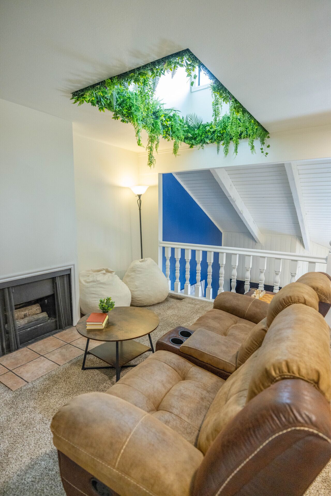 A cozy living room with a fireplace, a sofa set, a coffee table, and a staircase with a blue accent wall.