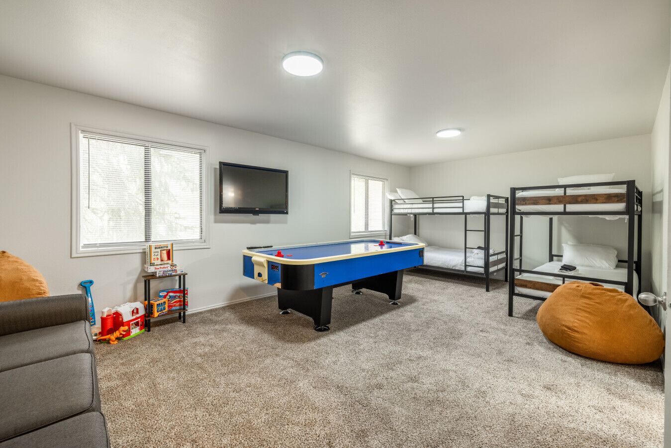 A room with bunk beds, a pool table, a television, and a window with blinds.