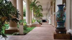 A corridor with columns, potted plants, and a large decorative vase. - Kauai Beachfront Escape with Pools & Spacious 1BR Resort Retreat (Lihue)
