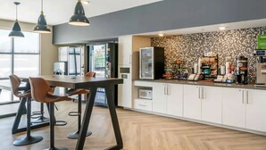 Un espace cuisine moderne avec un bar, des sièges et un mur arrière décoré d’un motif.
