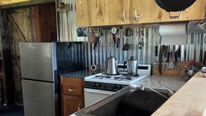 A kitchen with a marble countertop, stainless steel appliances, and hanging pots.
