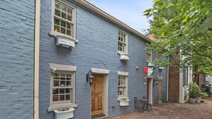 Un bâtiment traditionnel avec une façade bleue, une porte en bois et un chemin pavé de briques.