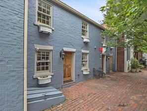 Ein traditionelles Gebäude mit blauer Fassade, einer Holztür und einem Ziegelweg.