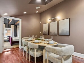 Un'area pranzo con un tavolo rotondo, sei sedie e un lampadario moderno.