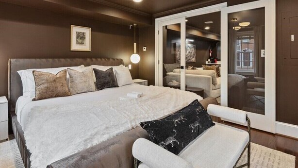 Une chambre à coucher avec un grand lit, des tables de chevet, une chaise et un luminaire au plafond.
