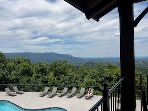 Ein Poolbereich mit Liegestühlen und Blick auf eine Berglandschaft.