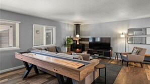 Una sala de estar moderna con mesa de billar, sofá, televisión y chimenea.