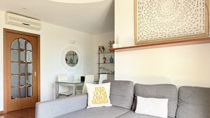 A living room with a grey sofa, a wooden door, a round mirror, and a decorative wall piece. - N317 - Numana, two-bedroom apartment with panoramic view (Numana)