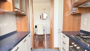 A kitchen with wooden cabinets, a gas stove, and a dining area with a white table and chairs. - N317 - Numana, two-bedroom apartment with panoramic view (Numana)