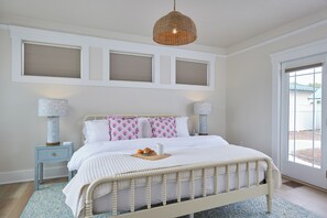 A bedroom with a bed, bedside lamps, a window, and a door. - Blue Gables 1920s Craftsman Near WWU 4BR 3BA Sleeps 9 Fenced Yard (College Place)