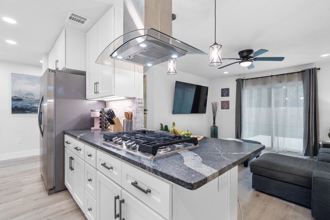 A modern kitchen with a central island, stainless steel appliances, and pendant lighting.