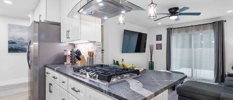 A modern kitchen with a central island, stainless steel appliances, and pendant lighting.