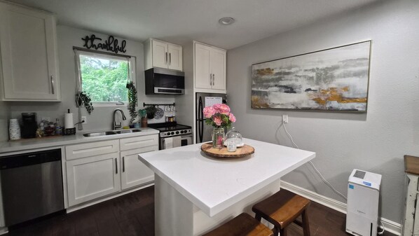 A kitchen with white cabinets, a central island, a sink, a stove, and a refrigerator.