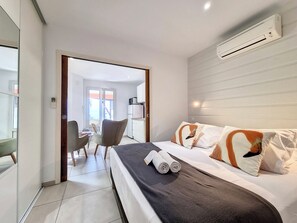 A hotel room with a bed, a desk, a chair, and an air conditioning unit. - Le Cardinal - Jacuzzi - Terrasse – AC (Les Avirons)