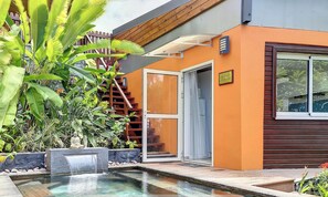 A modern building with an orange facade, a glass door entrance, a small outdoor pool, and a wooden staircase leading to a deck. - Aybowan - Jacuzzi - Climatisation (Les Avirons)