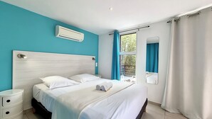 Ein Schlafzimmer mit einem Bett, einem Nachttisch, einer Klimaanlage und einem Fenster mit Vorhängen.