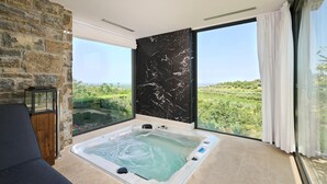 Et værelse med stort vindue, jacuzzi og stenvæg.